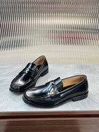 Prada unisex black leather loafers with metal strap and stitched moc-toe detailing.