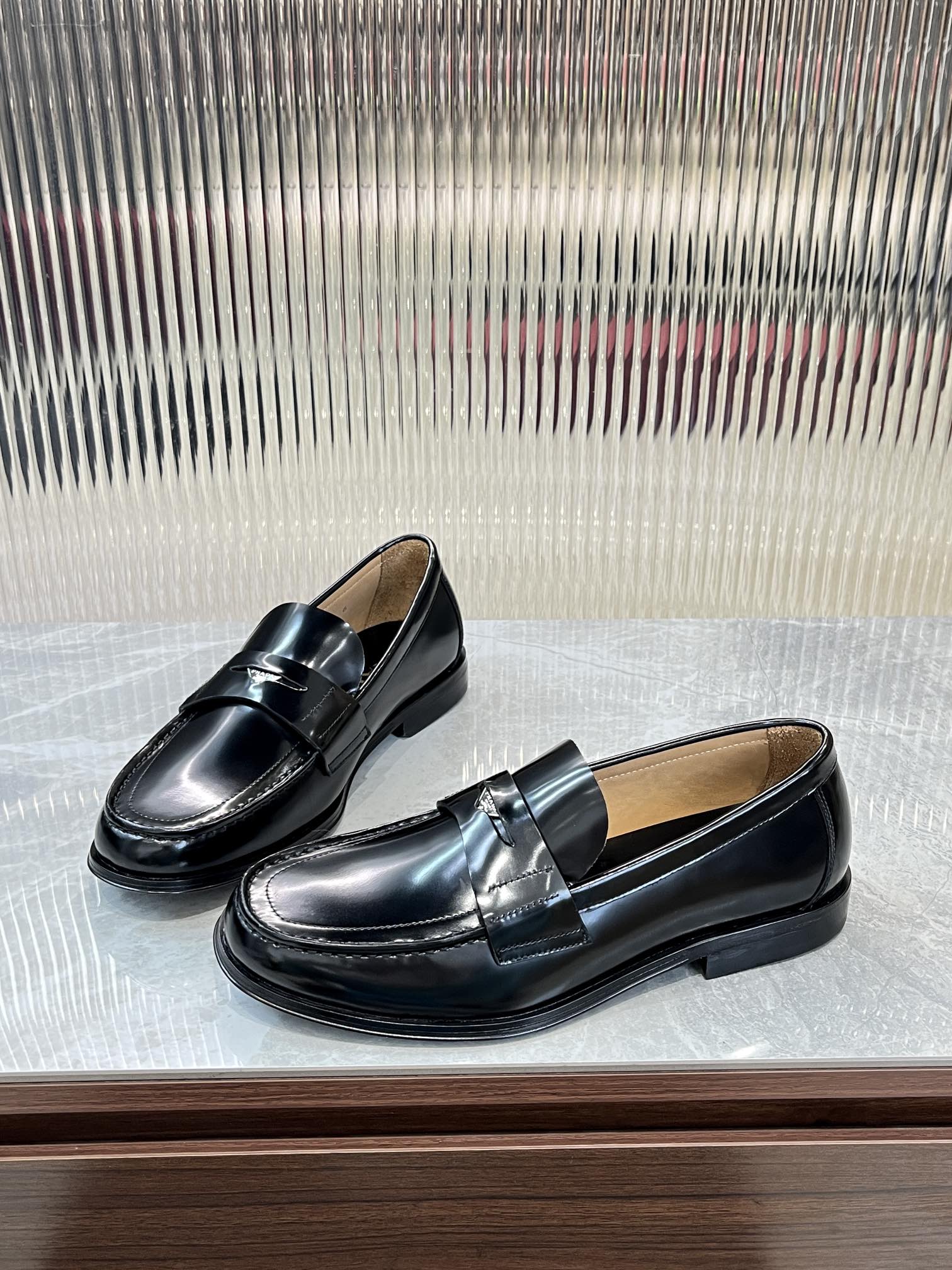 Prada unisex black leather loafers with metal strap and stitched moc-toe detailing.
