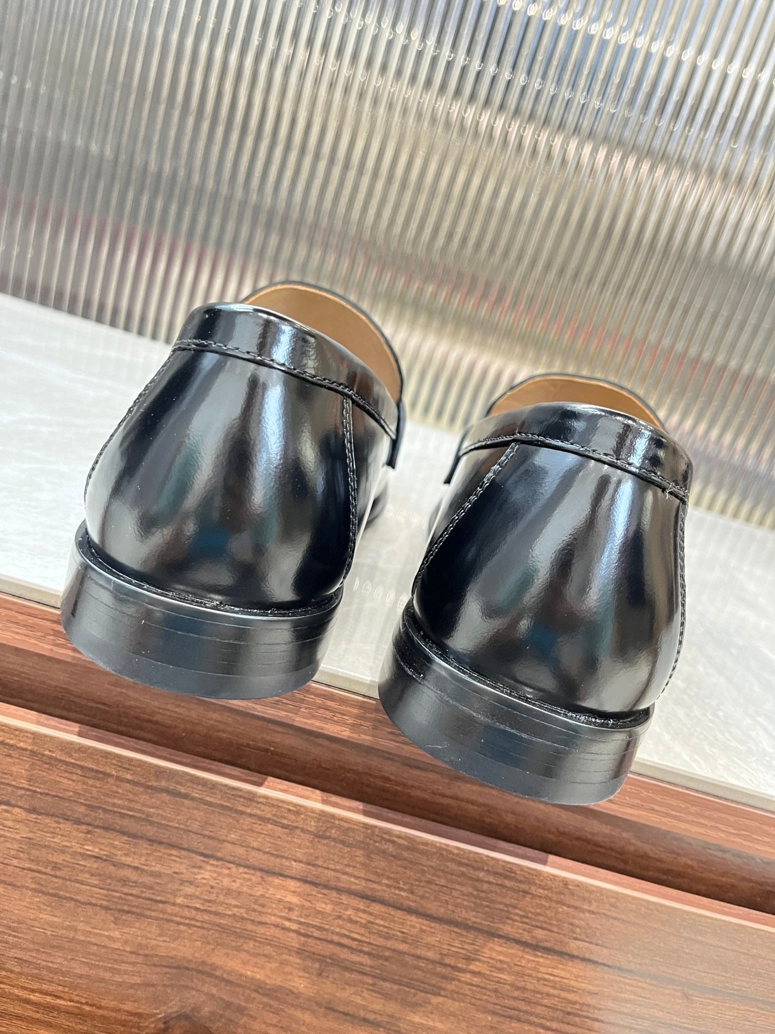 Prada unisex black leather loafers, rear view with low stacked heel and metal strap.