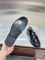 Prada unisex loafer soles shown with other black leather loafer with metal strap.