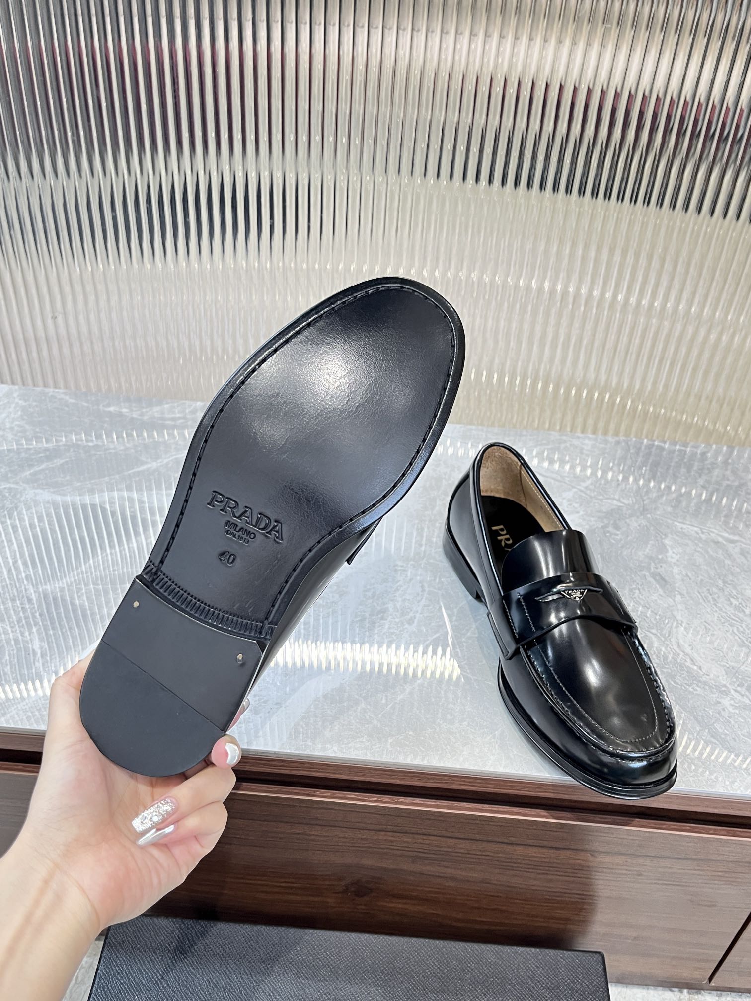 Prada unisex loafer soles shown with other black leather loafer with metal strap.
