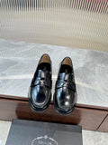 Prada unisex black leather loafer with metal strap across the vamp, polished finish.