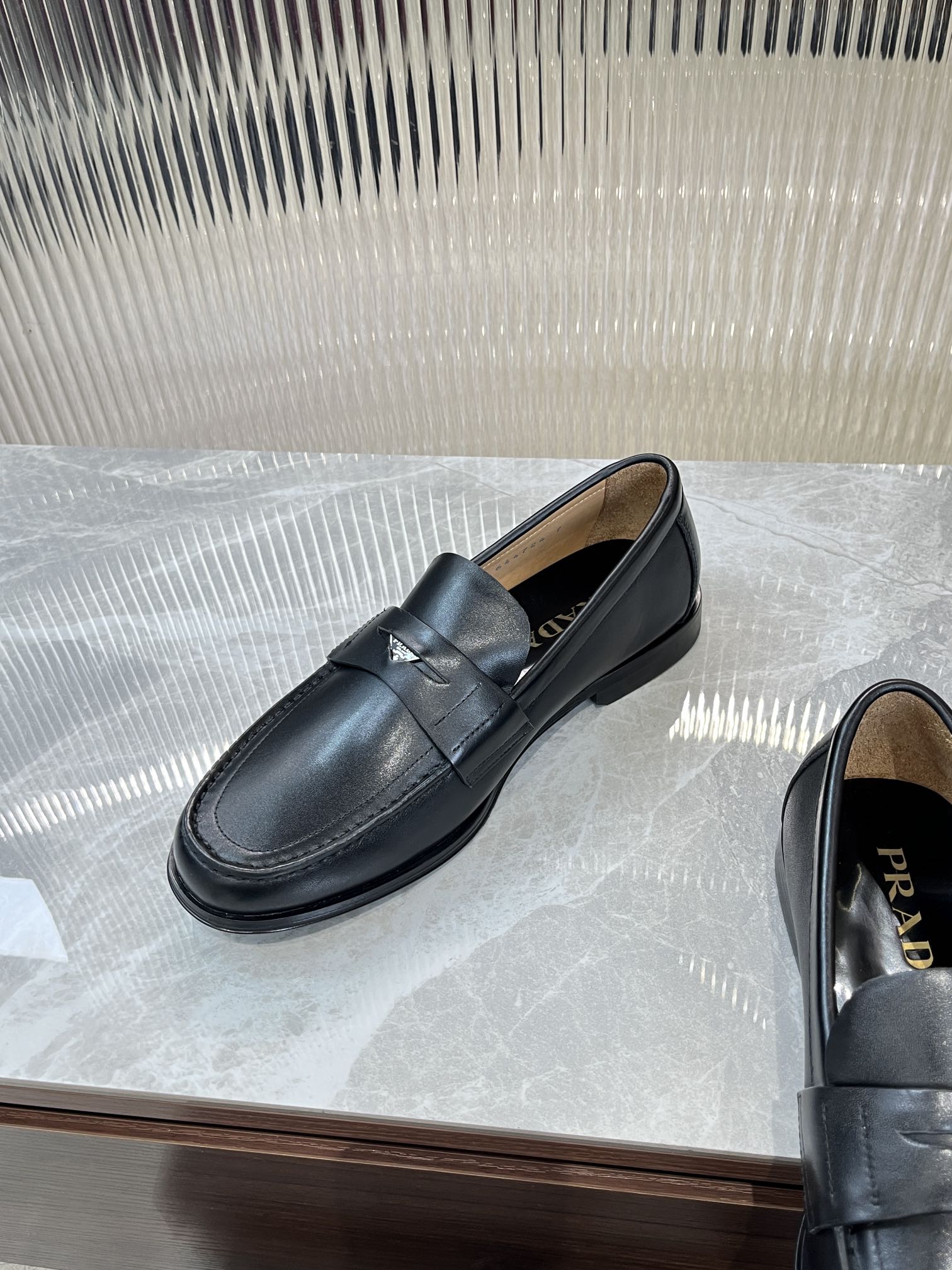 Prada unisex leather loafers, dark color, strap detail; tan lining visible