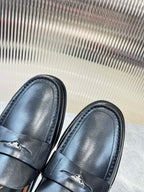 Prada leather loafers toe close-up, dark finish with strap stitching and emblem