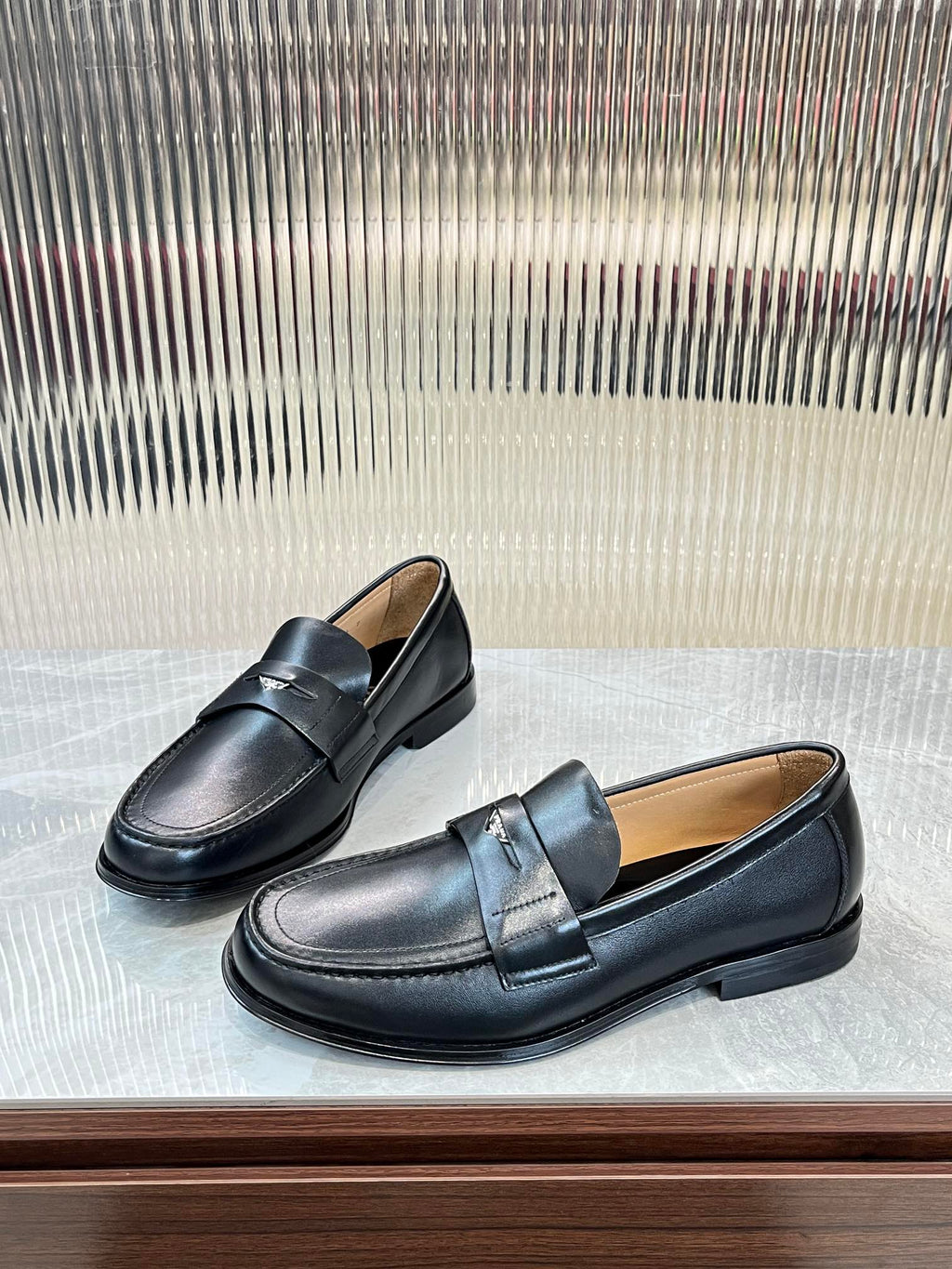 Prada unisex leather loafers, dark color, angled side view with strap detail