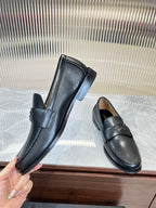 Prada unisex leather loafers, dark color, held pair shot with strap across vamp