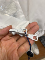 Louis Vuitton white jacket detail: cord with clip and hanging tag in hand