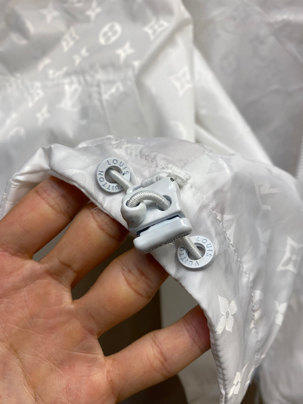 Louis Vuitton white jacket detail: adjustable snap hooks on monogram fabric