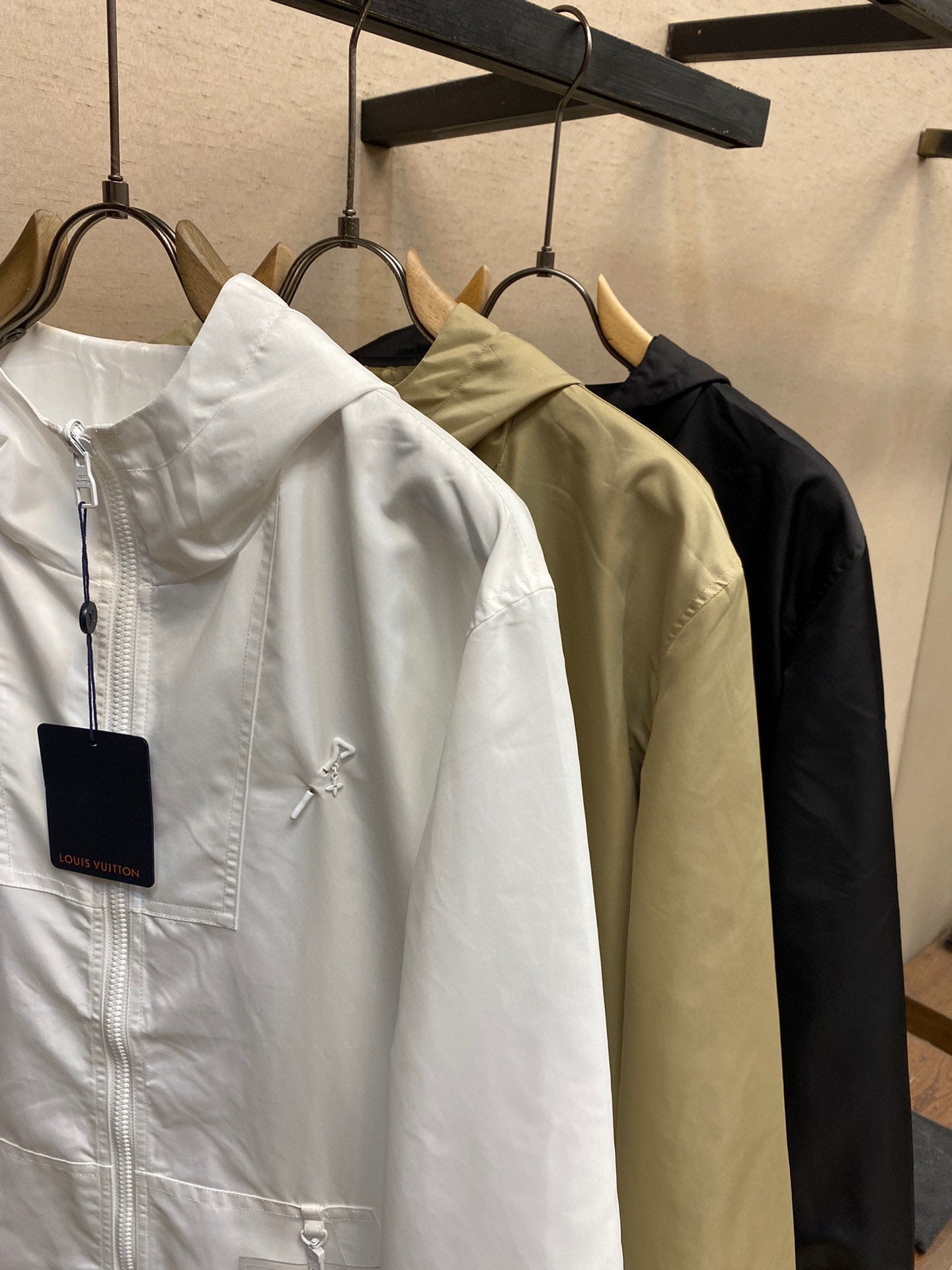 Set of hooded jackets on hangers: white, beige, and black