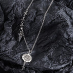 Silver-tone charm necklace with round medallion pendant, fleur-de-lis links, and small key charm
