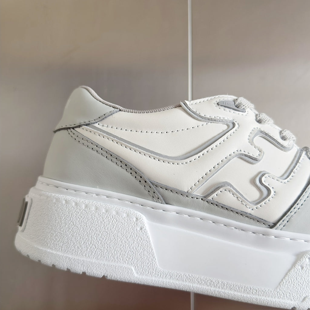 White Fendi unisex sneaker close-up, side panels with logo trim and lace-up hardware.