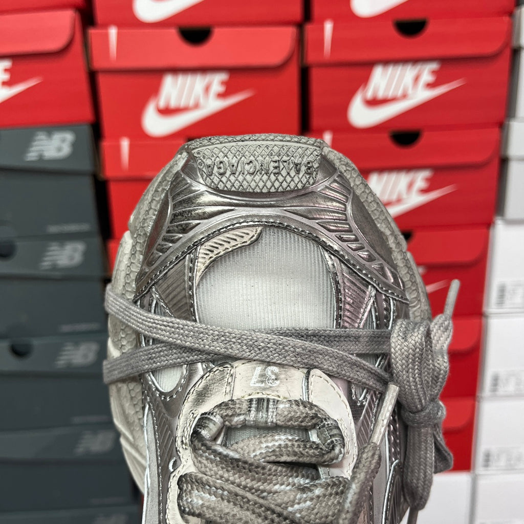 Silver metallic sneaker front with woven toe box, lace eyelets, and padded collar.