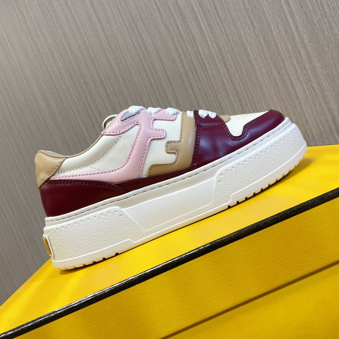 Low-top sneakers on a bright box, white sole with burgundy and blush color blocking