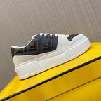 Low-top sneakers on yellow box, cream midsoles with dark logo quarters and white laces.