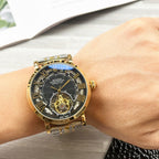 Rolex gold-tone wristwatch with black dial, open-heart movement, metal bracelet