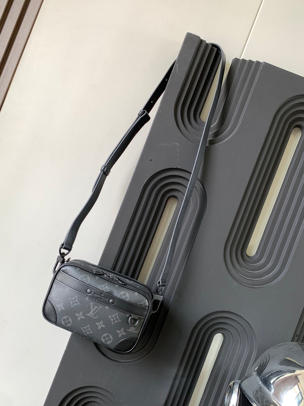 Crossbody bag with dark gray monogram canvas, adjustable shoulder strap and side zipper