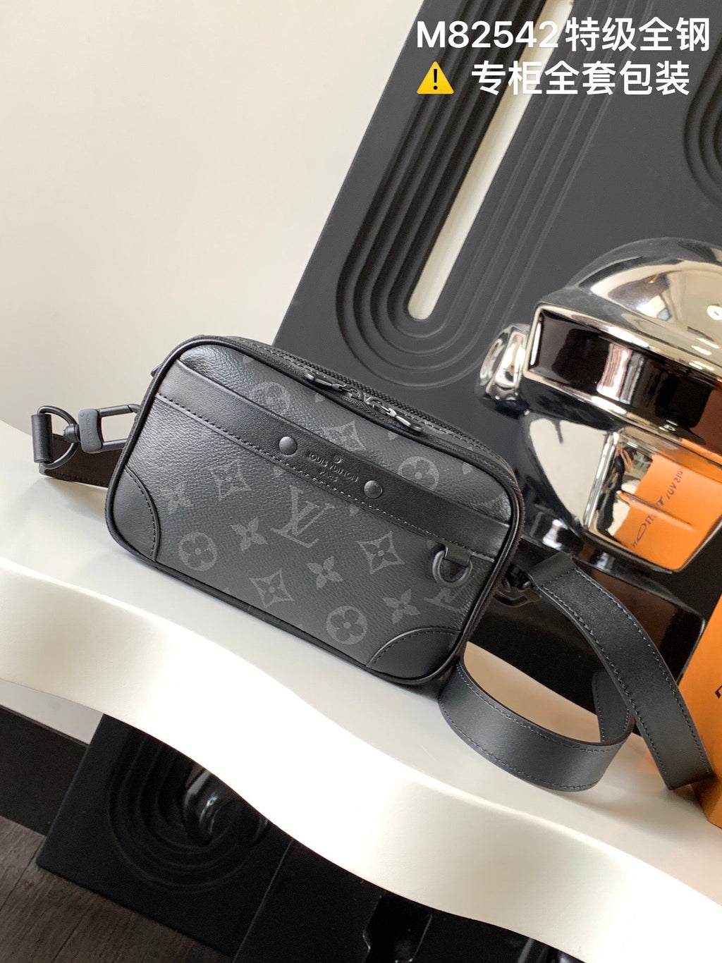 Crossbody bag with dark gray monogram canvas and top zipper, adjustable shoulder strap