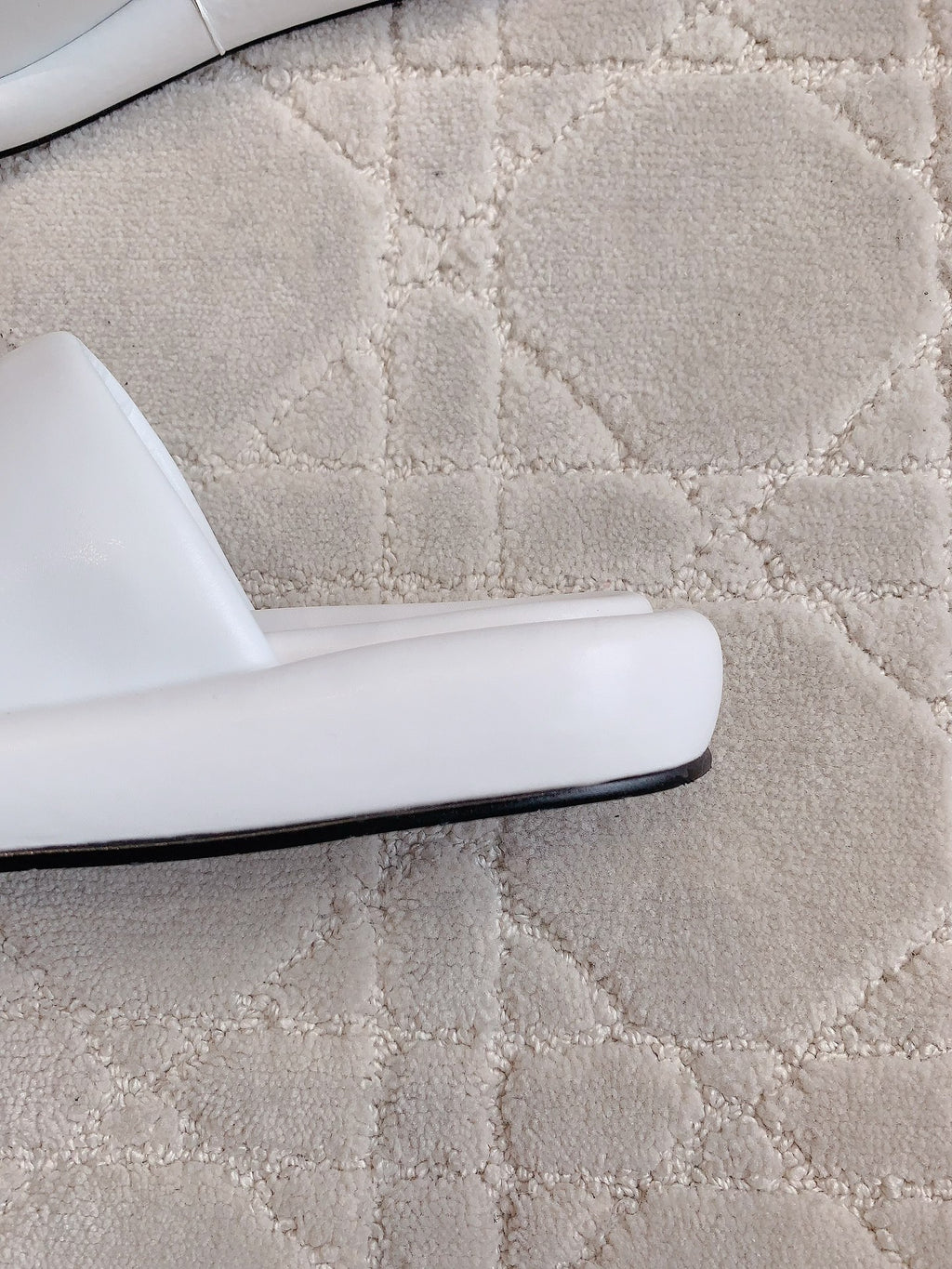 White slide sandal with flat sole and smooth side profile