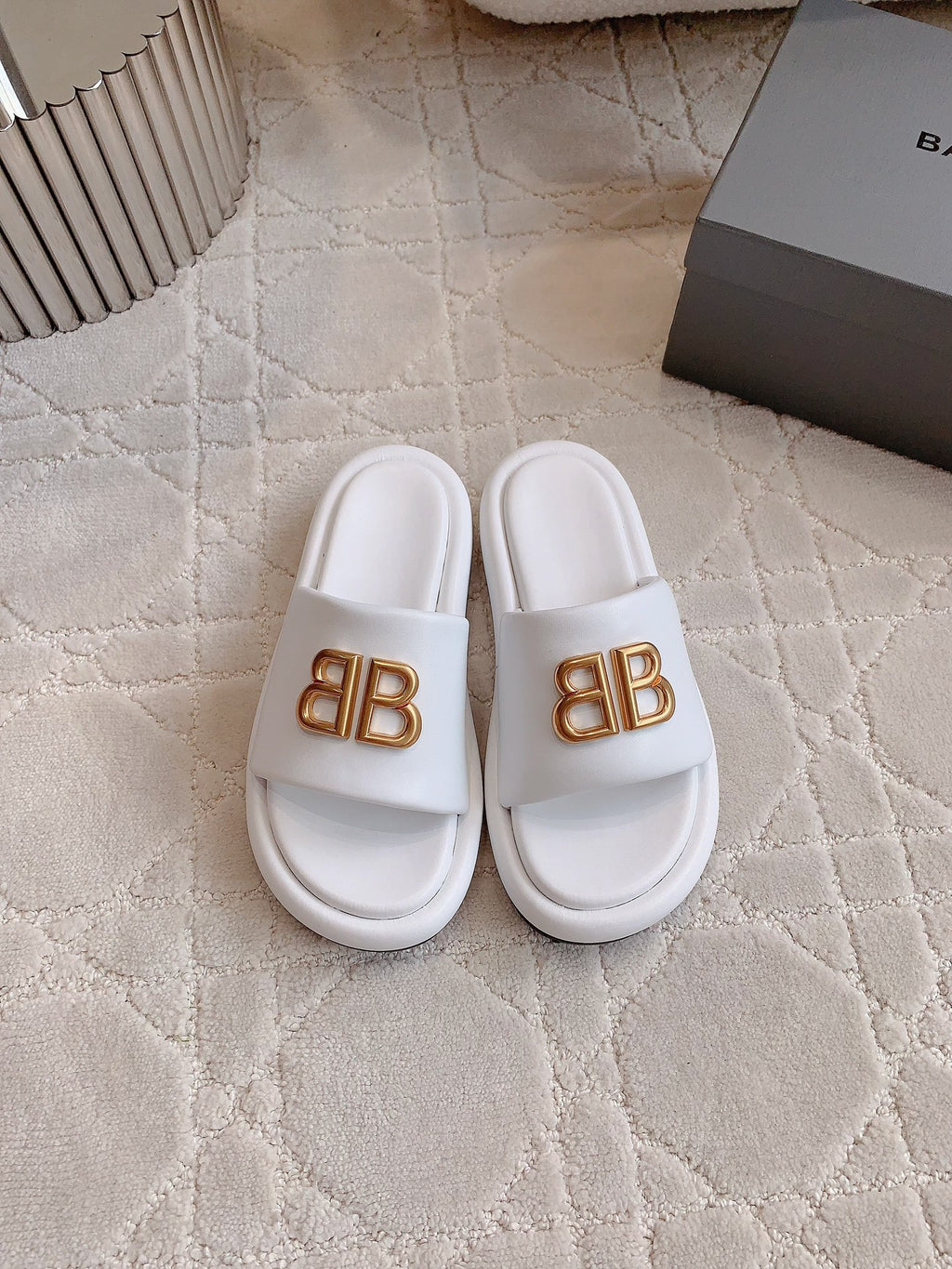 White slide sandals with gold BB buckle logo on single strap