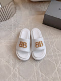 White slide sandals with gold BB buckle logo on single strap