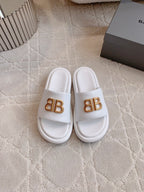 White slide sandals with gold BB buckle logo on single strap