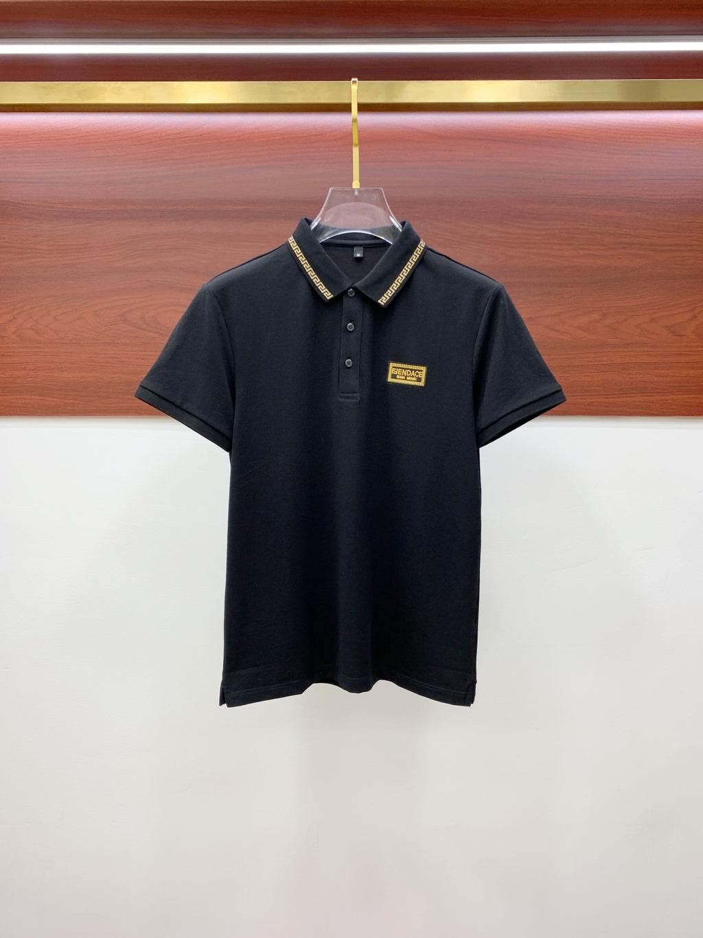 Versace black polo shirt with gold patterned collar trim and logo patch