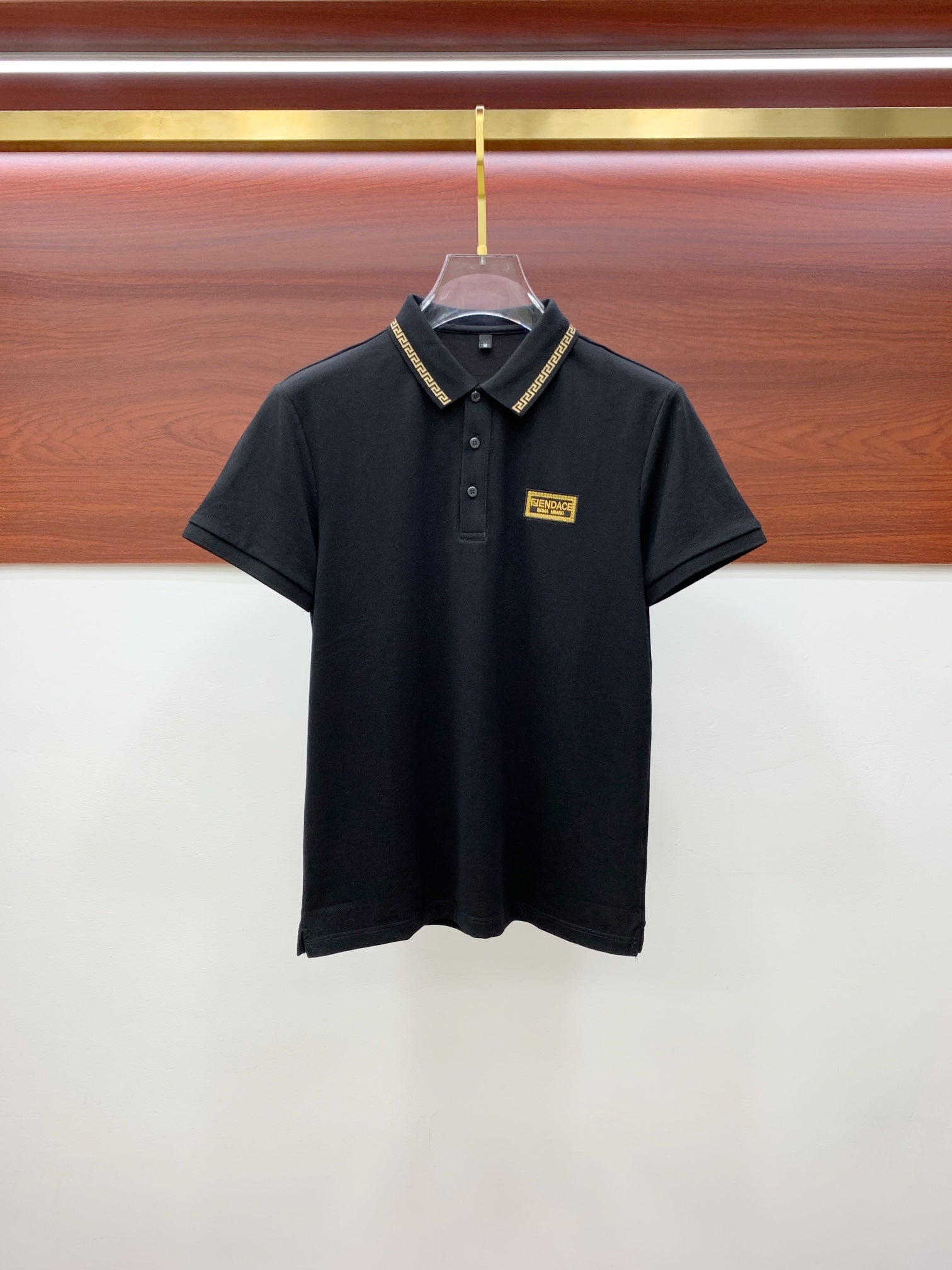Versace black polo shirt with gold patterned collar trim and logo patch