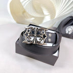 Dark leather belt with large ornate silver-tone buckle on a box