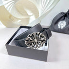 Dark faux-leather belt with ornate silver buckle on a box-ready display