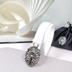 White leather belt with filigree silver-tone buckle, shown from side