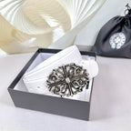 White leather belt with ornate silver-tone buckle on display box