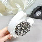 Handheld white leather belt with large silver-tone filigree buckle