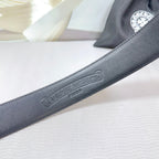Chrome belt strap close-up with embossed logo on dark leather finish.