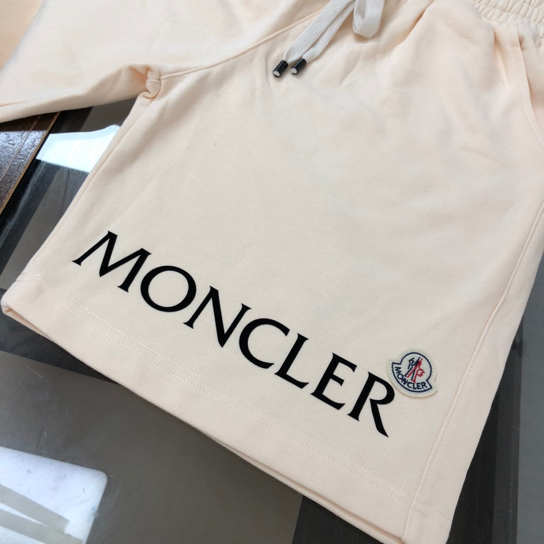 Cream shorts with large black MONCLER logo and small crest patch