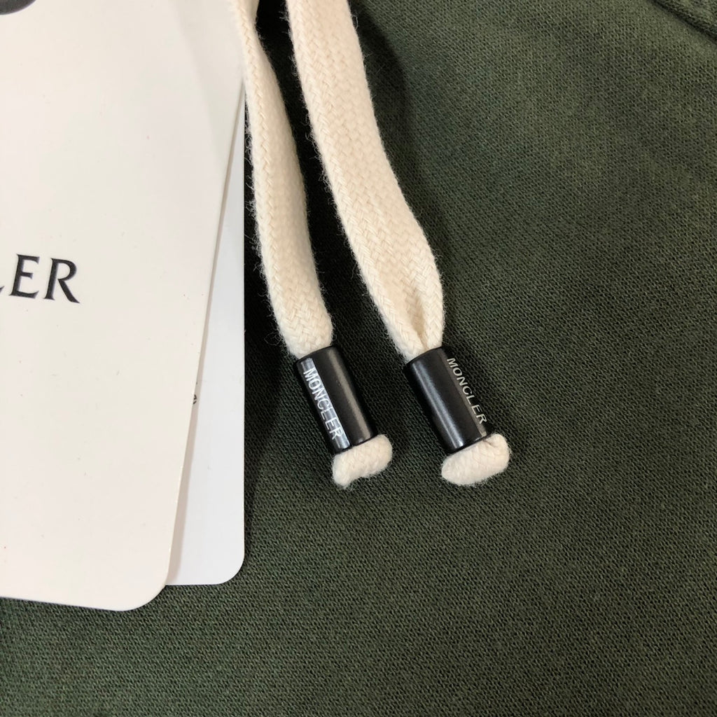 White drawstrings with black cord tips on dark green shorts