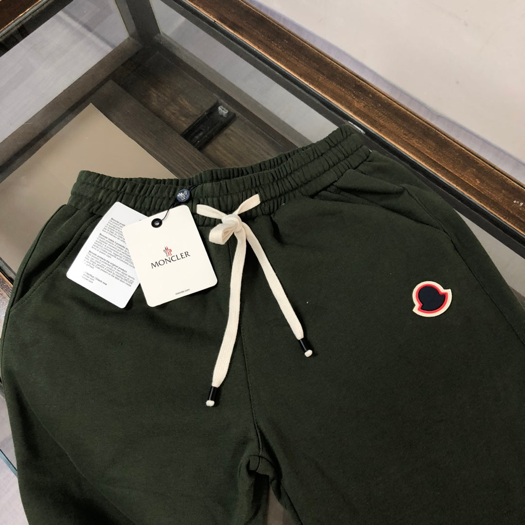 Dark green drawstring shorts with elastic waist, white drawstrings, and heart patch logo