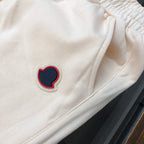 Cream shorts front with red-and-navy heart logo patch and drawstring cords