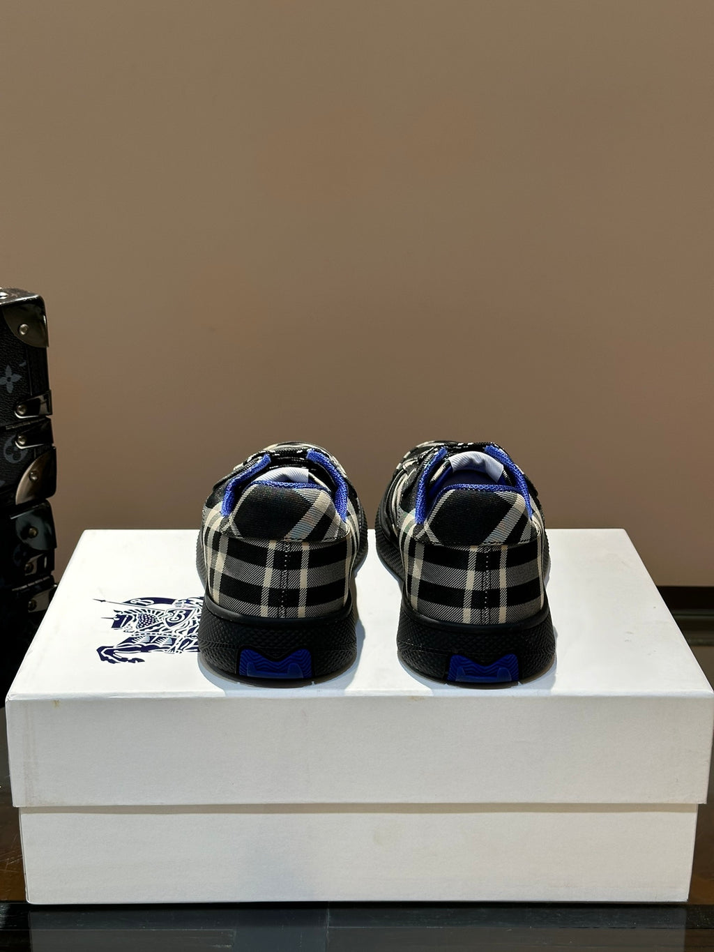 Back view of low-top sneakers with blue heel lining and black and white plaid uppers