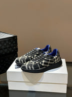 Angled view of low-top lace-up sneakers in black and white plaid with blue collar