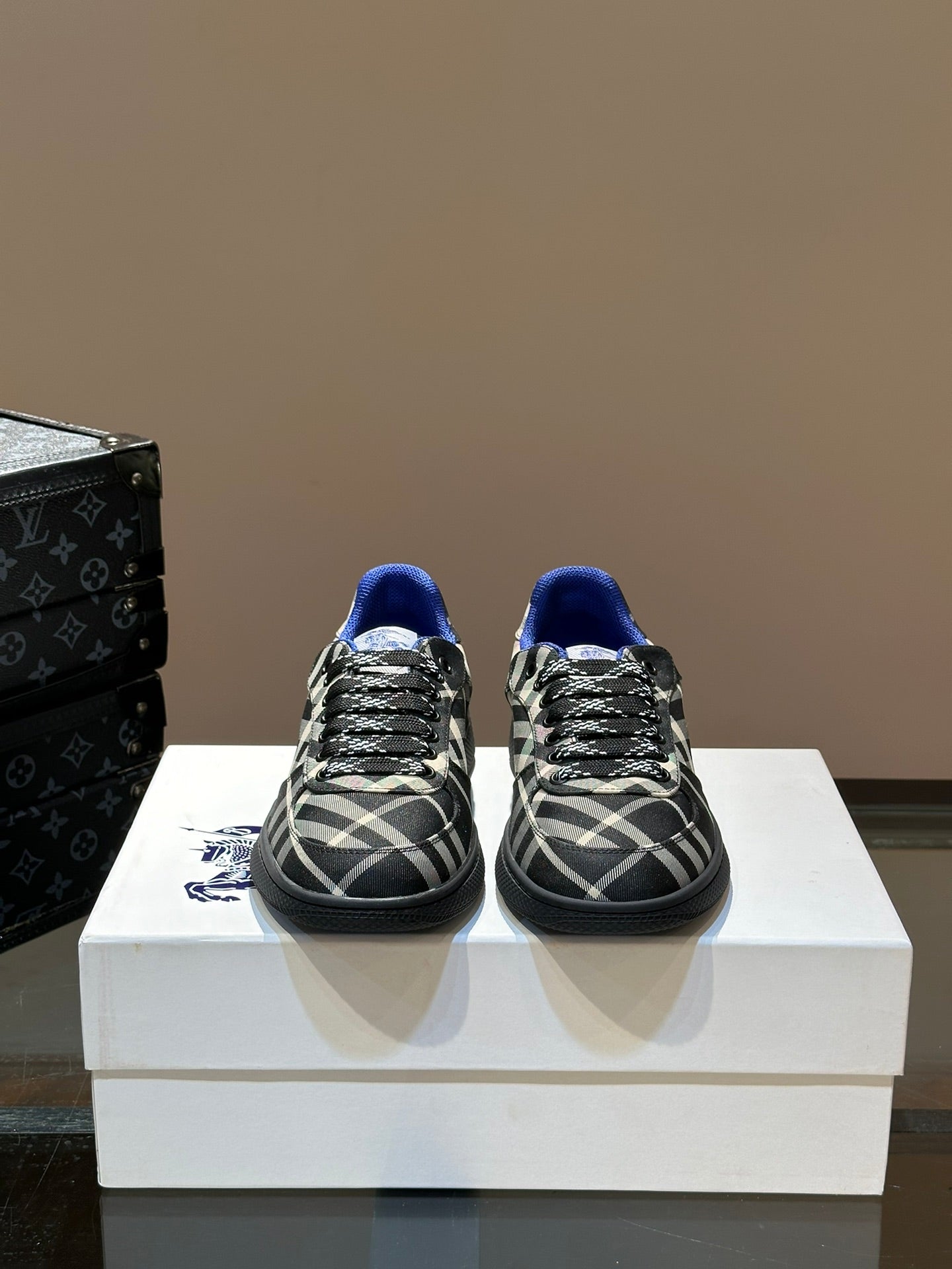 Pair of low-top lace-up sneakers in black and white plaid with blue accents