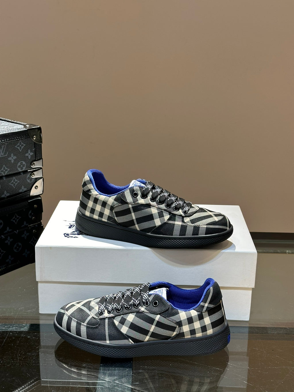Low-top lace-up sneakers on a box, black and white plaid with blue trim