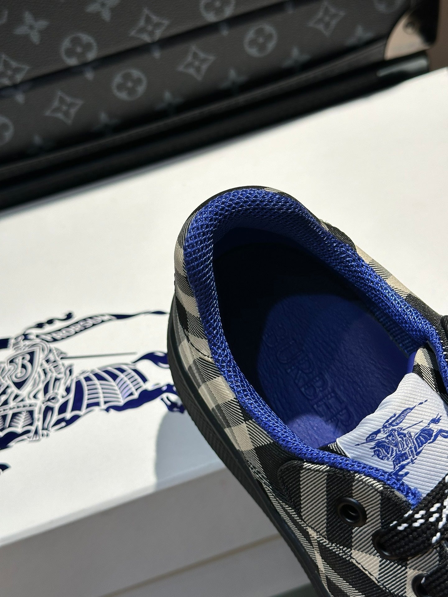 Close-up of sneaker interior with blue lining and black laces on plaid upper