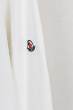 White sweatshirt sleeve with small embroidered logo patch