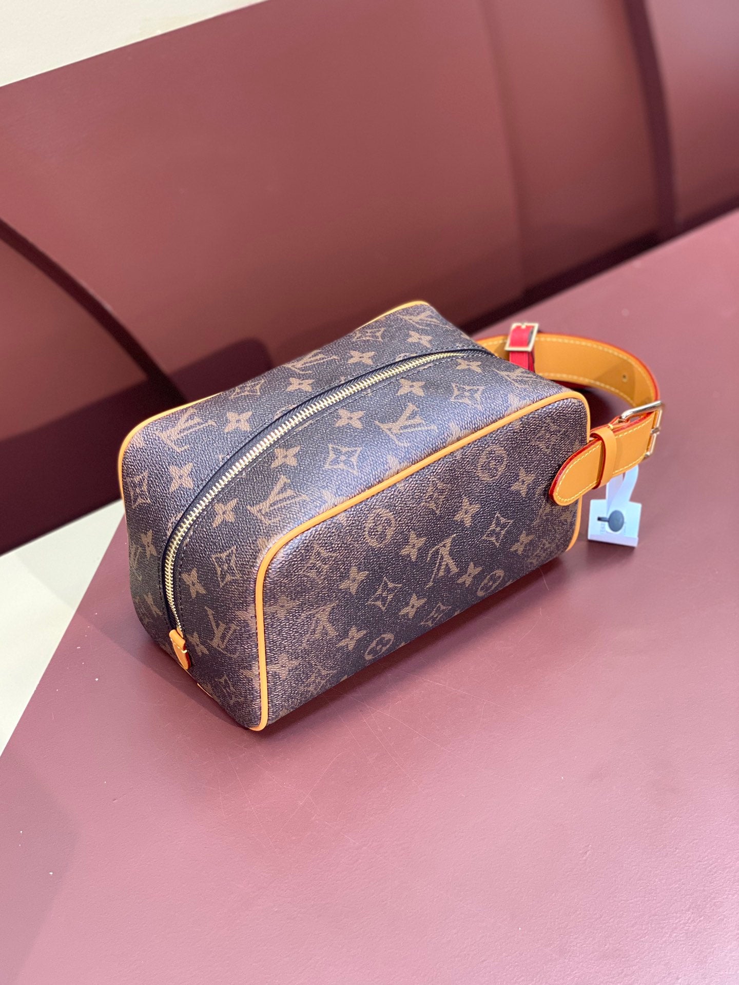 Louis Vuitton bag with brown monogram canvas, tan leather strap, gold zipper pull, charm