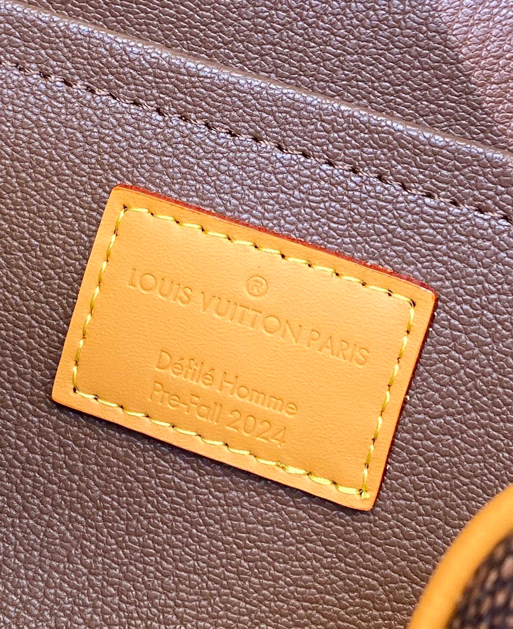 Louis Vuitton bag leather label close-up with tan stitched rectangle text