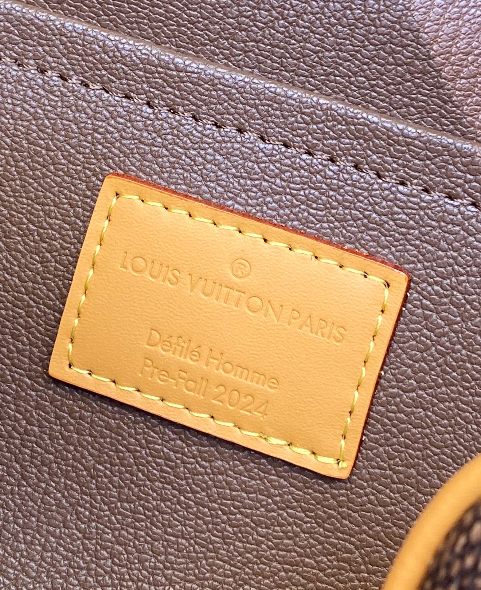 Louis Vuitton bag leather label close-up with tan stitched rectangle text