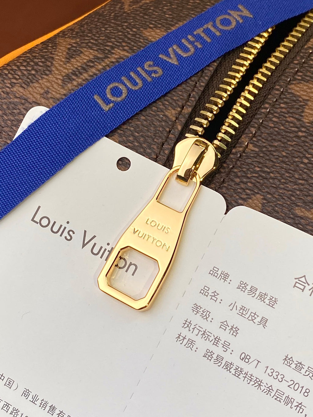 Louis Vuitton bag zipper pull with tan strap label card and blue webbing strap