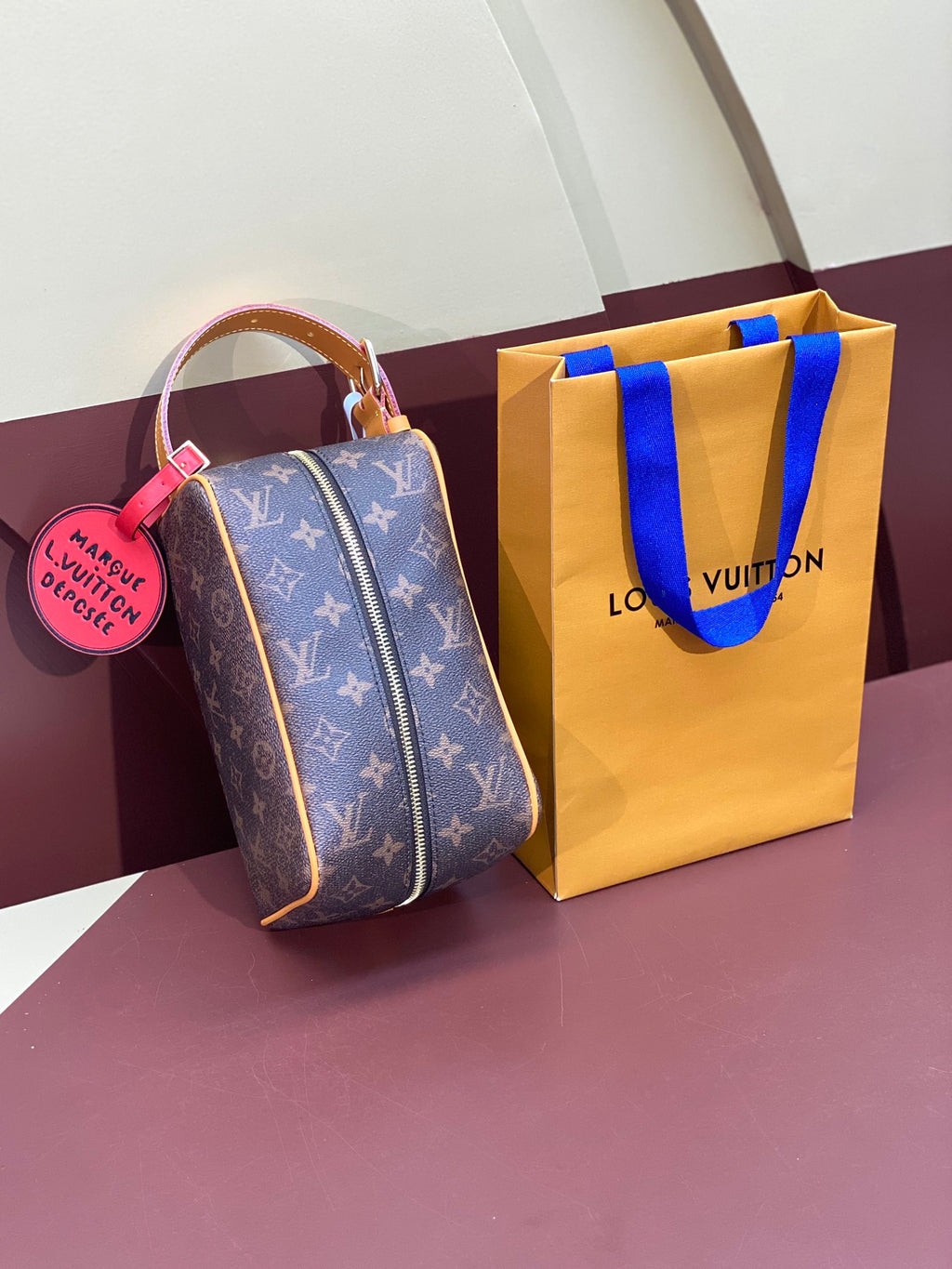 Louis Vuitton bag standing with pink luggage tag and tan-and-blue shopping bag