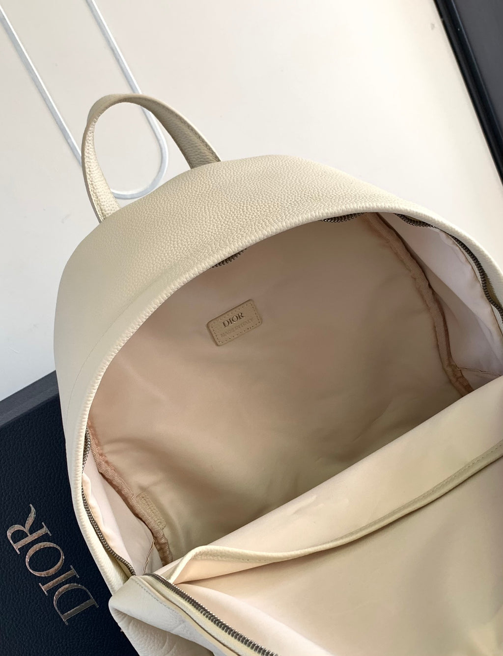 Cream open-top backpack with fabric-lined interior and zipper edge.