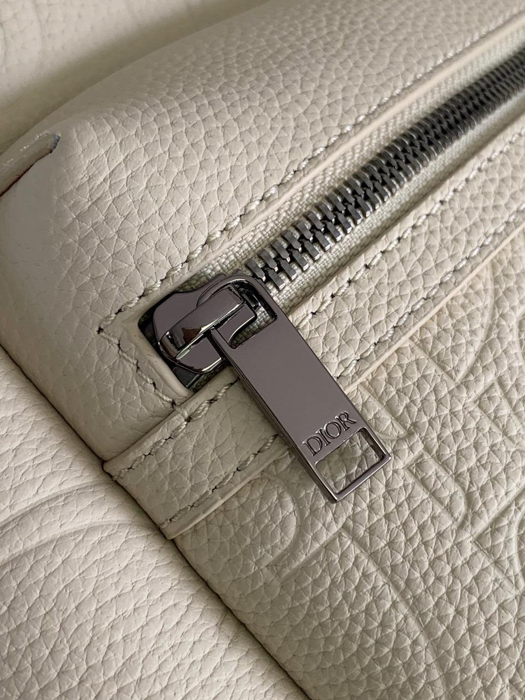 Cream backpack with metal zipper pull and Dior logo tag on interior pocket.